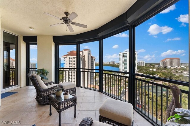 sunroom featuring tile patterned flooring, a textured ceiling, and a water view