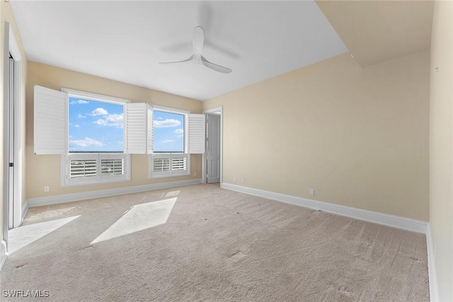 carpeted spare room with ceiling fan and baseboards