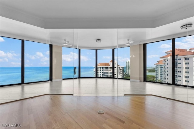 empty room with a wall of windows, wood finished floors, ornamental molding, and a water view