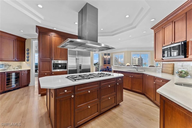 kitchen featuring appliances with stainless steel finishes, island range hood, wine cooler, a tray ceiling, and recessed lighting