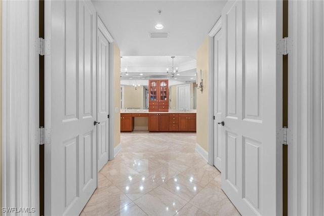 corridor with baseboards, a chandelier, a tray ceiling, and recessed lighting