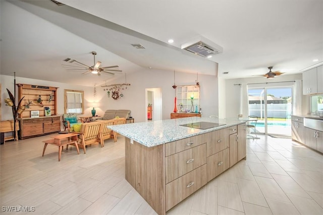 kitchen with a center island, vaulted ceiling, ceiling fan, black electric cooktop, and light stone countertops