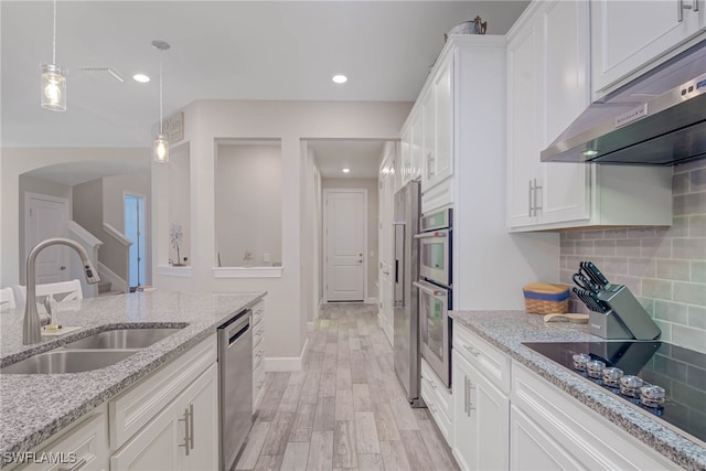 kitchen with light stone countertops, appliances with stainless steel finishes, white cabinetry, tasteful backsplash, and sink