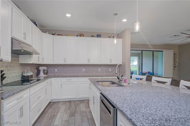 kitchen featuring black electric cooktop, dishwasher, white cabinets, a breakfast bar, and sink