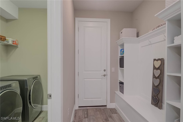 laundry room with washing machine and dryer and light hardwood / wood-style flooring