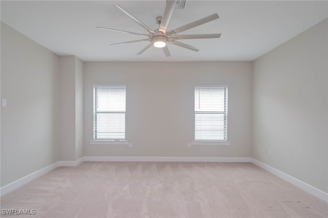 spare room with ceiling fan, light colored carpet, and plenty of natural light