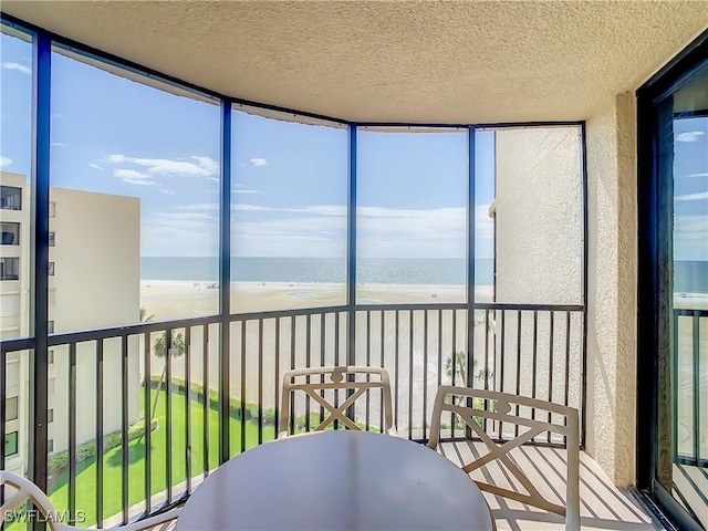 sunroom featuring a view of the beach and a water view