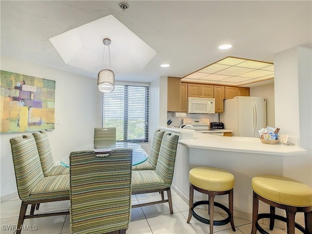 kitchen with a kitchen bar, light tile patterned floors, kitchen peninsula, pendant lighting, and white appliances