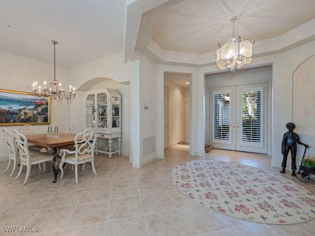 tiled dining space featuring beam ceiling, french doors, and an inviting chandelier