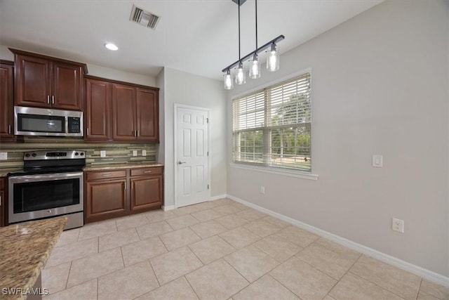 kitchen with light stone counters, pendant lighting, light tile patterned floors, backsplash, and appliances with stainless steel finishes