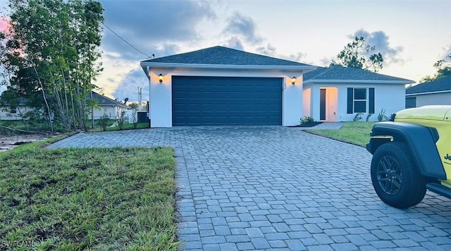 single story home with a garage, stucco siding, decorative driveway, and a front yard