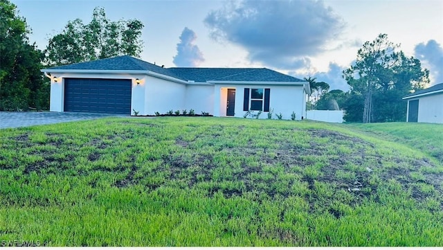 single story home with a garage, stucco siding, decorative driveway, and a front yard