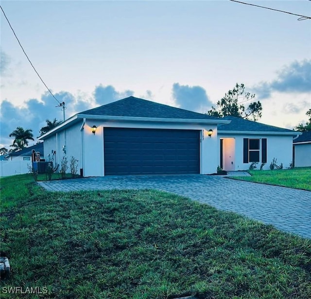 ranch-style home with a garage, a front yard, fence, and stucco siding