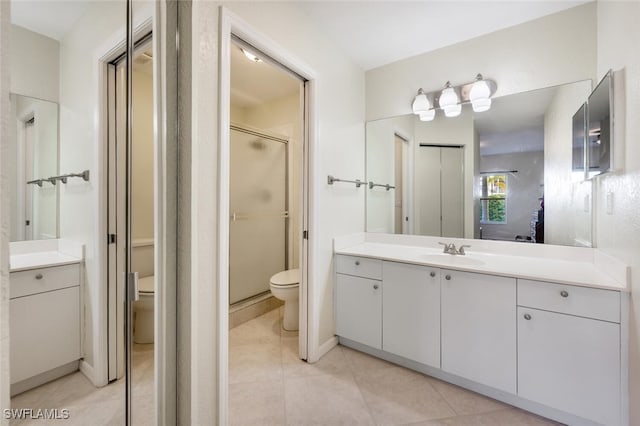 bathroom with tile patterned floors, toilet, a shower with door, and vanity