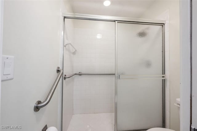 bathroom featuring a shower with shower door and toilet