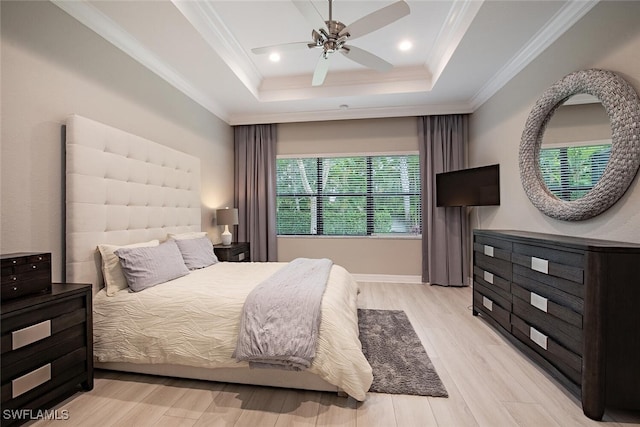 bedroom featuring crown molding, a tray ceiling, light hardwood / wood-style floors, and ceiling fan