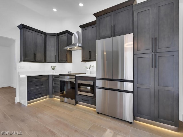 kitchen featuring appliances with stainless steel finishes, light wood-type flooring, and wall chimney exhaust hood