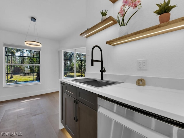 kitchen with sink, decorative light fixtures, stainless steel dishwasher, and light stone countertops