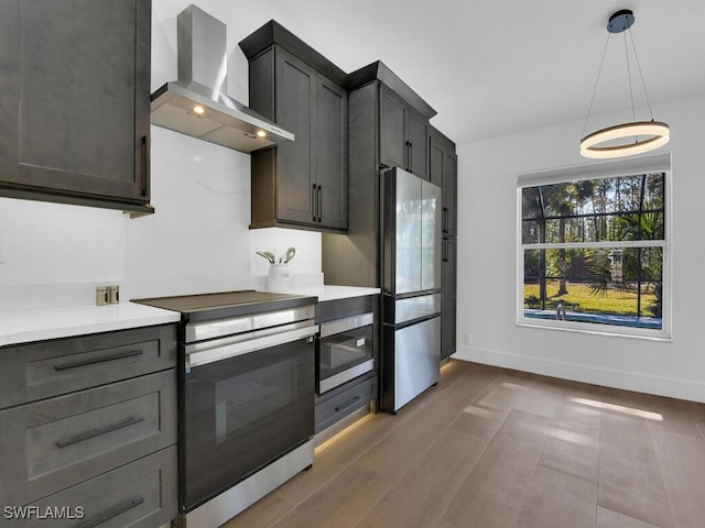 kitchen with refrigerator, stainless steel range with electric stovetop, hanging light fixtures, dark wood-type flooring, and wall chimney exhaust hood