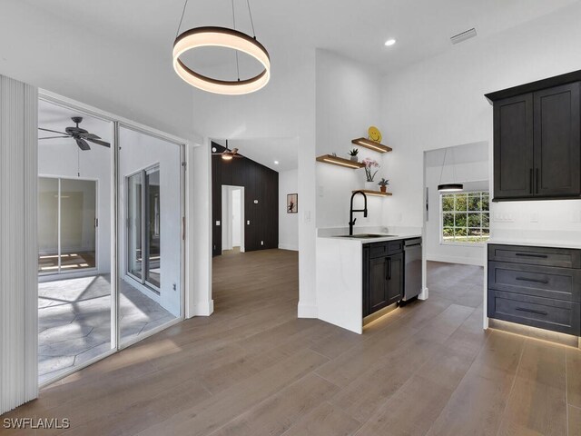 kitchen with ceiling fan, wood-type flooring, sink, and a towering ceiling