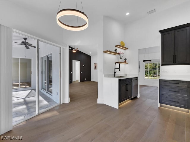 kitchen featuring a high ceiling, wood-type flooring, sink, and ceiling fan