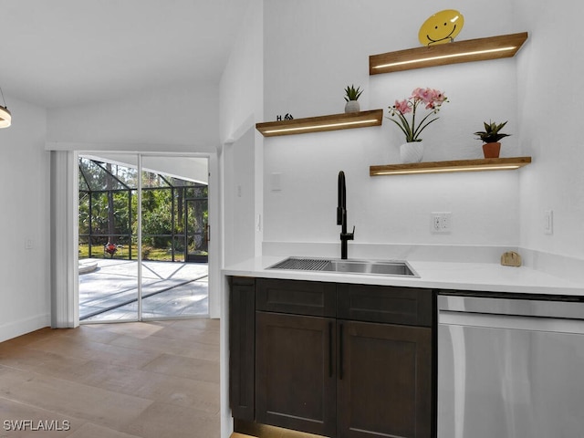 kitchen featuring vaulted ceiling, stainless steel dishwasher, dark brown cabinetry, and sink