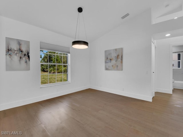 unfurnished dining area with wood-type flooring and vaulted ceiling