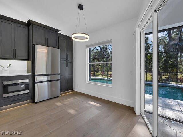 kitchen with pendant lighting, appliances with stainless steel finishes, and light hardwood / wood-style floors