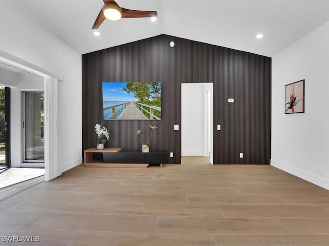 living room with ceiling fan, vaulted ceiling, and light wood-type flooring