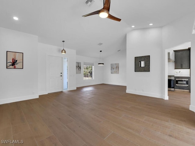 unfurnished living room with vaulted ceiling, ceiling fan, and light hardwood / wood-style flooring