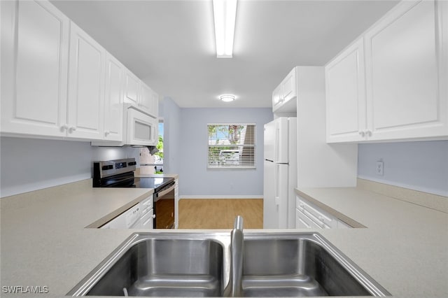 kitchen with white cabinets, white appliances, hardwood / wood-style floors, and sink