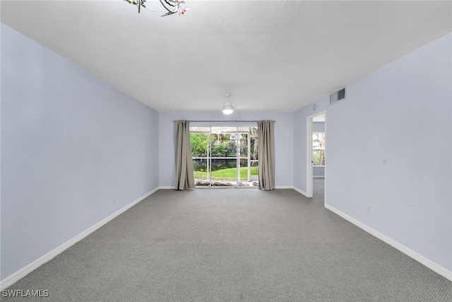 carpeted empty room featuring an inviting chandelier