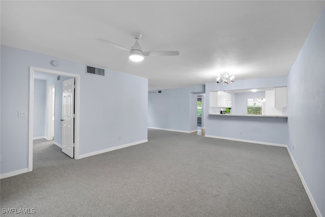 unfurnished living room featuring ceiling fan with notable chandelier and carpet