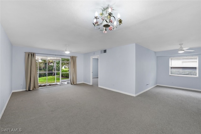 carpeted empty room featuring ceiling fan with notable chandelier and plenty of natural light