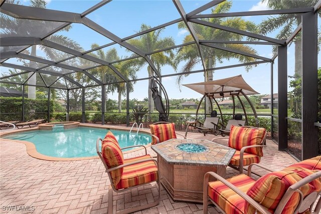 view of pool featuring an outdoor fire pit, a patio area, glass enclosure, and an in ground hot tub