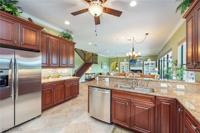 kitchen with sink, ornamental molding, ceiling fan with notable chandelier, hanging light fixtures, and appliances with stainless steel finishes