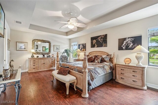 bedroom featuring a raised ceiling, ceiling fan, and dark hardwood / wood-style flooring