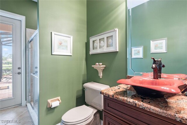 bathroom featuring toilet, tile patterned floors, walk in shower, and vanity