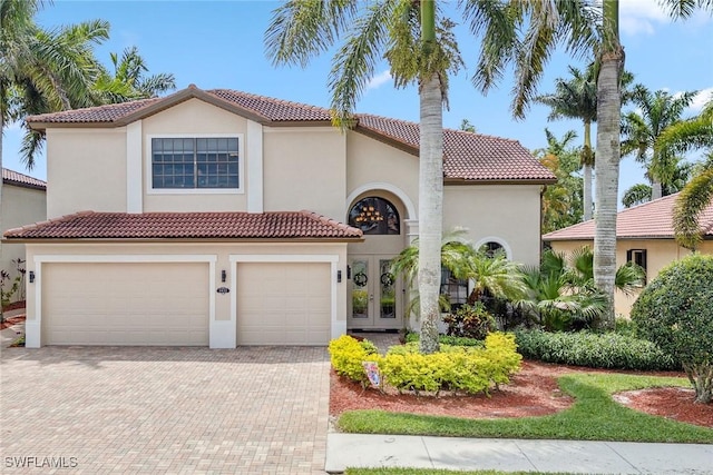 mediterranean / spanish house with a garage and french doors