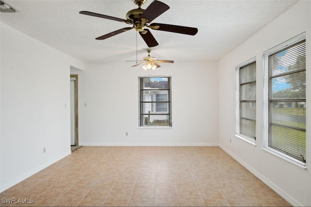 tiled spare room with a textured ceiling and a wealth of natural light