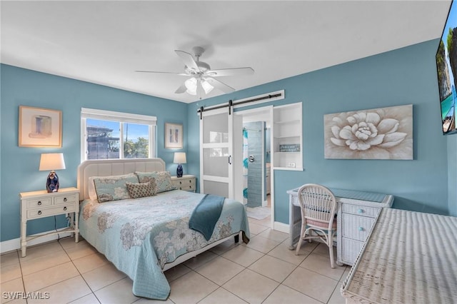 bedroom with ceiling fan, a barn door, and light tile patterned floors