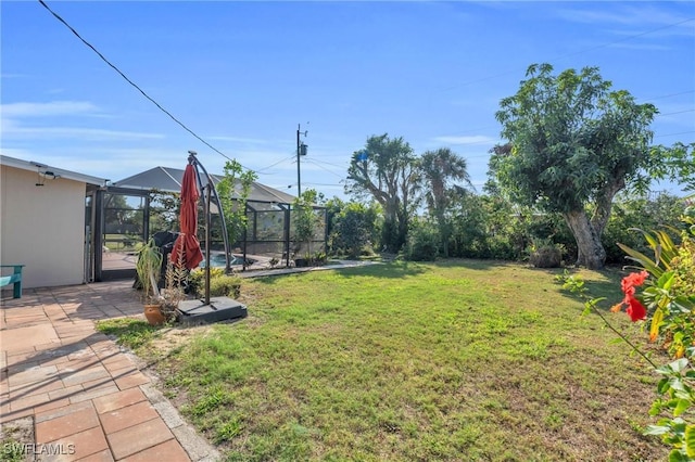 view of yard with glass enclosure and a patio area