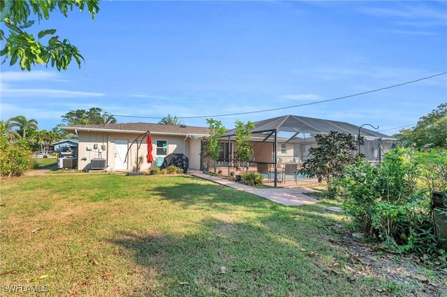 view of front of house featuring a lanai, a front lawn, a patio, and central AC unit