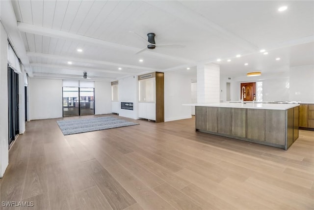 interior space featuring a spacious island, sink, wood ceiling, beamed ceiling, and ceiling fan