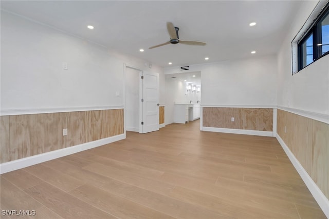 empty room with a wainscoted wall, light wood-style floors, and recessed lighting