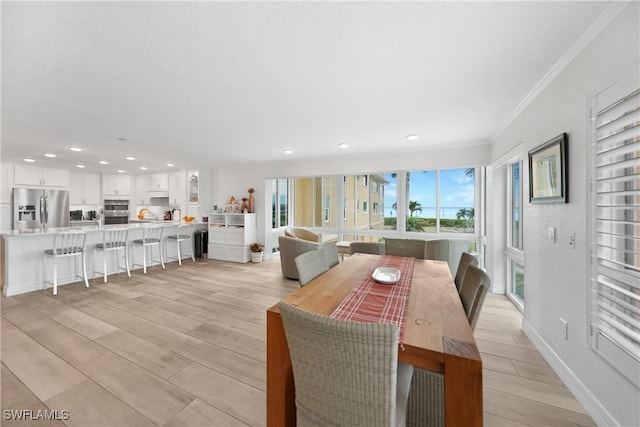 dining area with light hardwood / wood-style flooring and ornamental molding