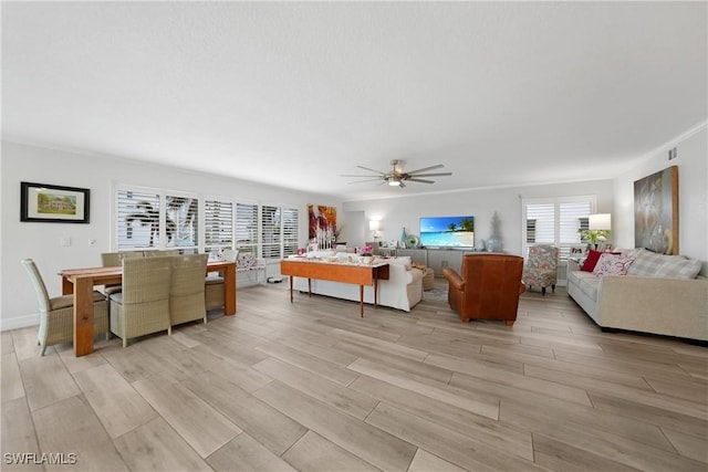 living room with ceiling fan, crown molding, and light hardwood / wood-style flooring