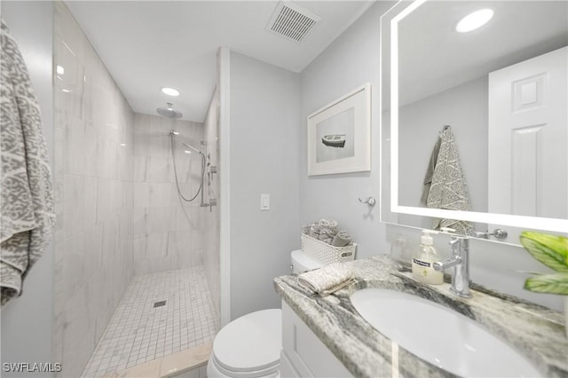 bathroom with tiled shower, vanity, and toilet