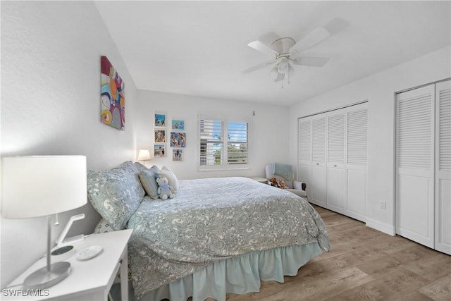 bedroom with light hardwood / wood-style floors, ceiling fan, and multiple closets