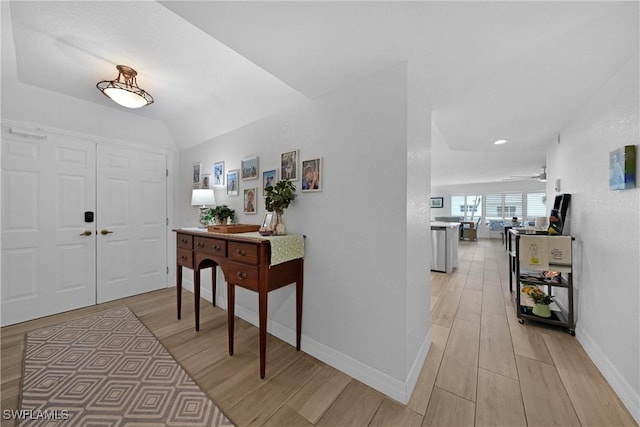 entryway with ceiling fan, vaulted ceiling, and light wood-type flooring